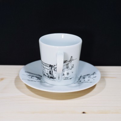 Chávena de café branca com desenho preto de paisagem e respectivo pires