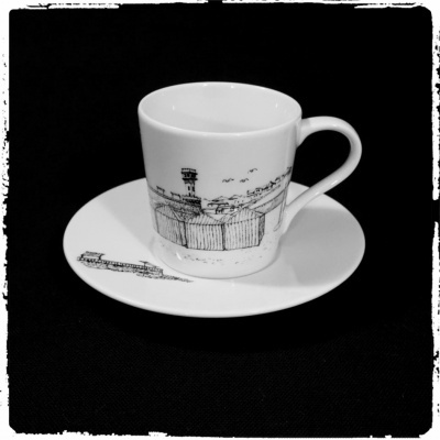 Chávena e pires de cerâmica branca com desenho urbano a preto