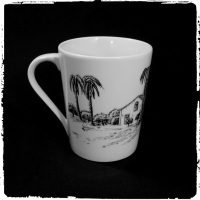 Caneca branca com ilustração preta de palmeiras e casa numa paisagem rural