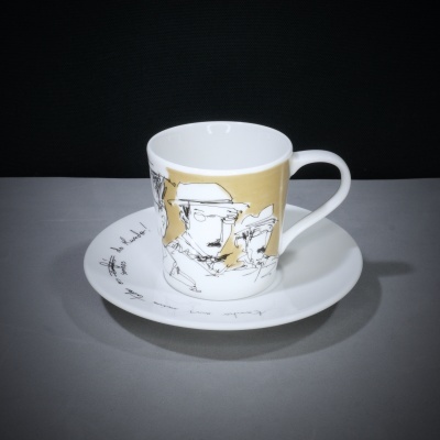 Chávena e prato brancos com ilustrações em preto e dourado