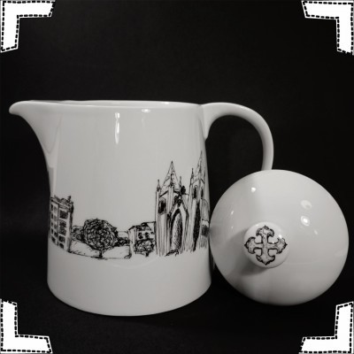 Jarros brancos em cerâmica com desenho preto de edifícios e árvore, e tampa com cruz em relevo