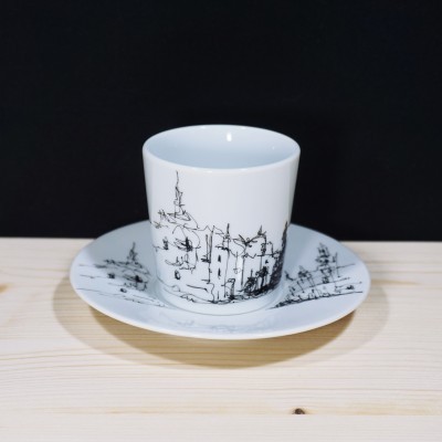 Conjunto de chávena e pires em porcelana branca com desenho urbano em preto.