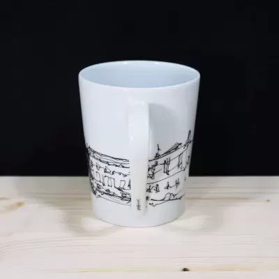 Detalhe da pega de uma caneca de porcelana branca com a palavra Coimbra escrita verticalmente