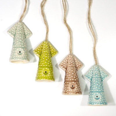 Ornamentos em cerâmica coloridos em forma de flecha suspensos por cordas.