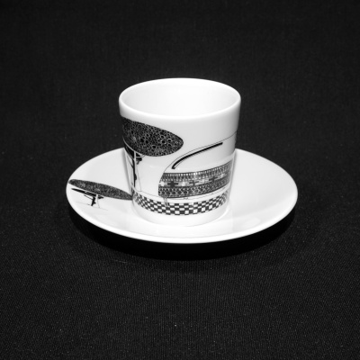 Chávena e pires brancos com desenhos pretos sobre fundo preto