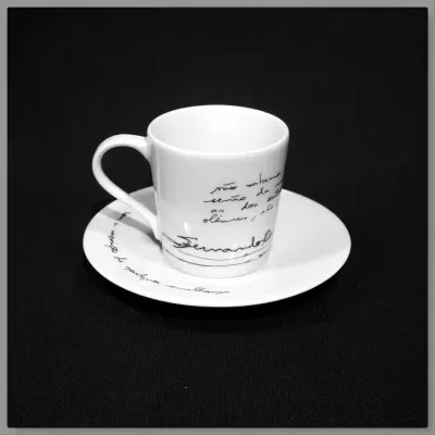 Chávena de café de porcelana branca com pires, mostrando excertos de poemas manuscritos