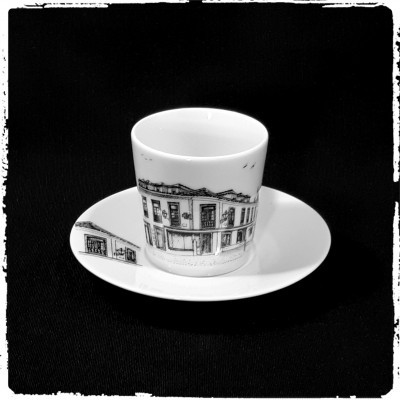 chávena e prato de porcelana branca com desenhos a preto de edifícios