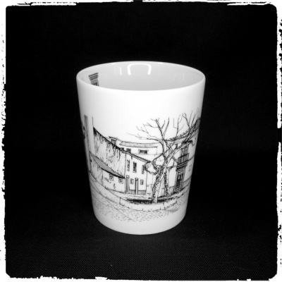 Copo de cerâmica com desenho de casas e árvore em preto sobre fundo preto