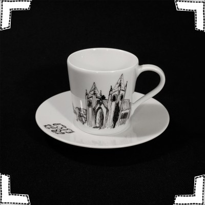 Chávena e pires de porcelana branca com ilustração a preto de edifícios góticos