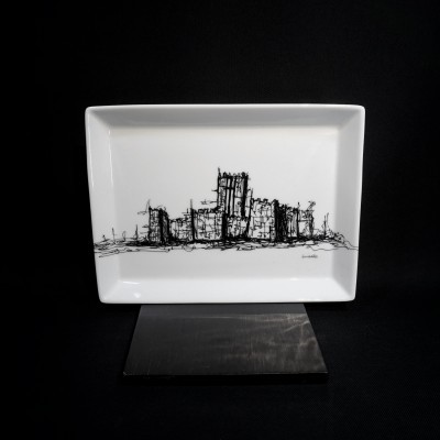 Prato retangular branco com desenho a preto de uma cidade estilizada sobre suporte preto