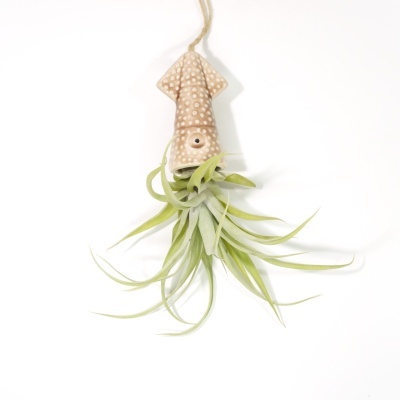 Planta artificial suspensa em suporte de cerâmica bege com textura