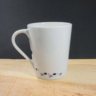 Caneca branca com padrão preto na base em superfície de madeira