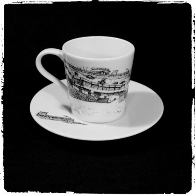 Conjunto de chávena e pires brancos com ilustrações a preto de comboio.