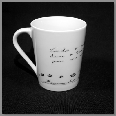 Caneca branca com texto manuscrito e desenhos geométricos pretos.