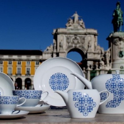 Conjunto de chá de porcelana branca com padrões azuis geométricos numa praça com monumentos ao fundo