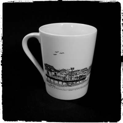 Caneca branca com desenho preto de edifícios e aves