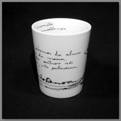 Copo branco de cerâmica com escrita manuscrita preta em fundo preto