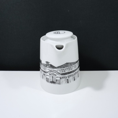 Bule branco de cerâmica com desenho preto de edifício e tampa circular