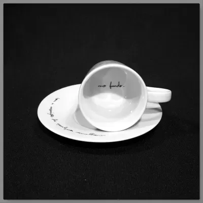 Vista de perto do interior de uma chávena de café de porcelana branca, revelando a frase manuscrita