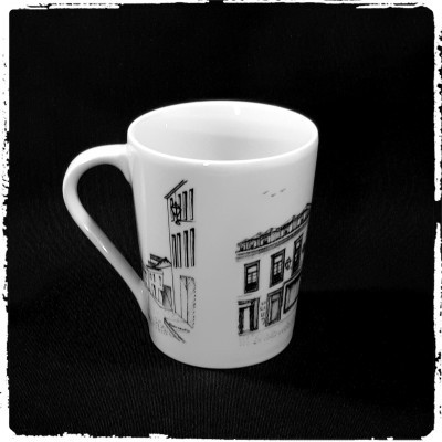 Caneca branca com desenhos de edifícios em preto