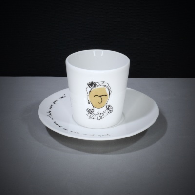 Chávena branca com desenho e pires com texto em fundo cinzento