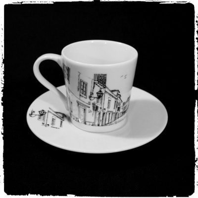 chávena e pires em porcelana branca com desenho preto de rua e edifícios