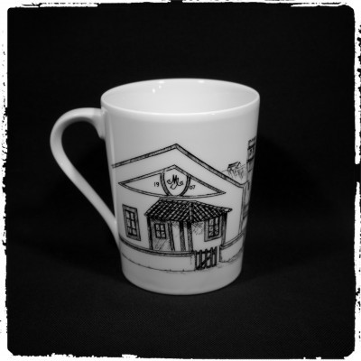 Caneca branca com desenho preto de casa e texto 1907 M E