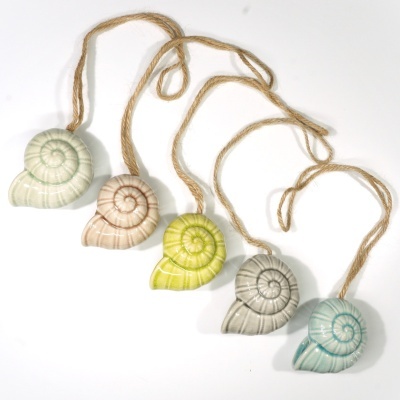 Cinco conchas de cerâmica coloridas penduradas em cordões de cânhamo