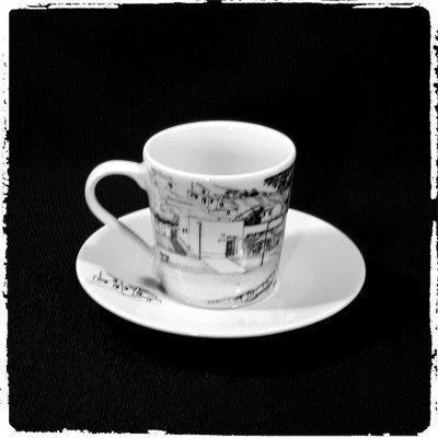 chávena de cerâmica branca com desenho a preto e pires branco