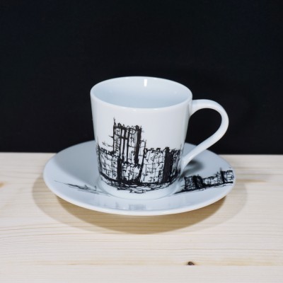 Conjunto de chávena e prato brancos com desenho preto de castelo