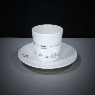 Chávena branca com texto e desenhos a preto num pires branco