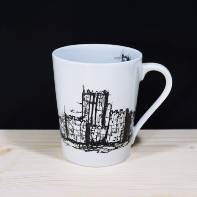 Caneca branca de cerâmica com desenho preto de edifício, sobre superfície de madeira clara.