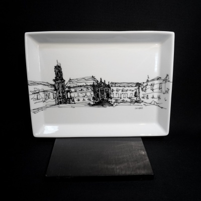 Prato retangular branco com desenho preto de edifícios e assinatura COIMBRA.