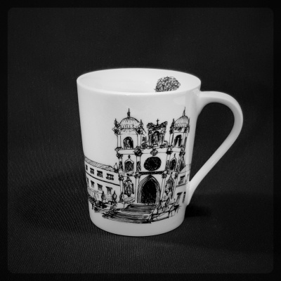 Caneca branca de cerâmica com desenho preto de edifício histórico