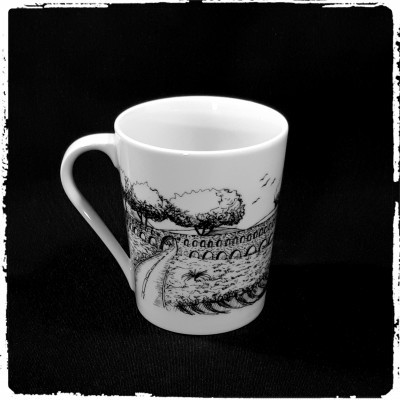 Caneca branca com desenho preto de aqueduto e mar