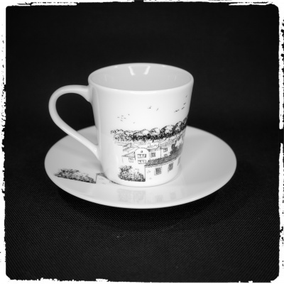 Chávena e pires em porcelana branca com desenho a preto de casas e árvores