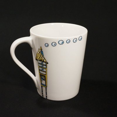 Caneca branca de cerâmica com ilustração colorida de casa e pequenas imagens circulares azuis
