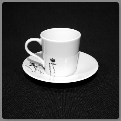 chávena branca com pires decorado com flores negras sobre fundo preto