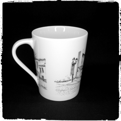 Caneca branca com desenho preto de edifícios e postes de luz