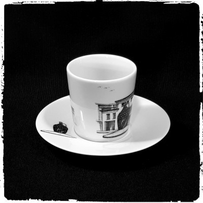 Xícara e pires de porcelana branca com desenhos pretos e cinza