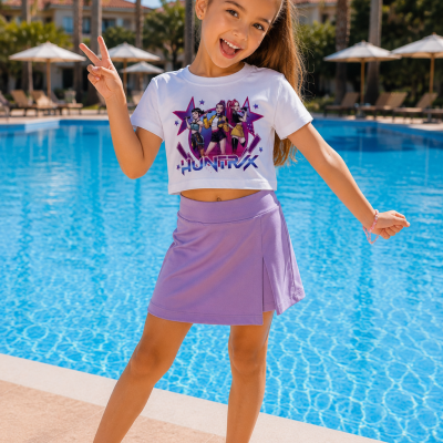 Menina perto de piscina com top branco estampado e saia lilás.