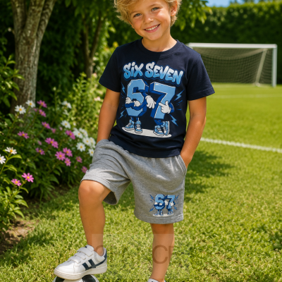 Menino loiro com t-shirt azul escura e calções cinzentos sobre relvado com bola de futebol