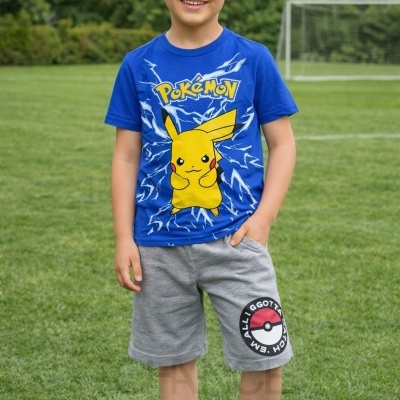 Menino com t-shirt azul Pokémon, calções cinza com símbolo de pokébola e ténis brancos num campo de futebol