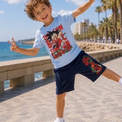 Menino com roupa Dragon Ball a sorrir e fazer sinal de vitória perto do mar