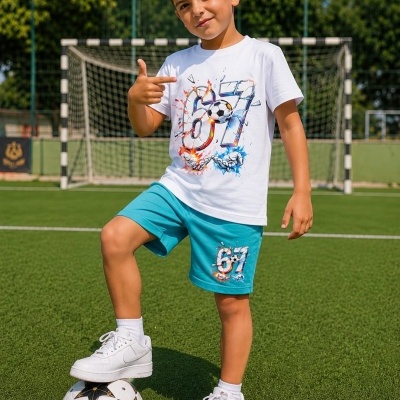 Menino com conjunto infantil e bola de futebol num campo de futebol