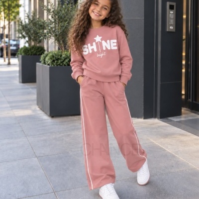 Criança com conjunto cor-de-rosa claro com estampado SHINE bright numa rua urbana