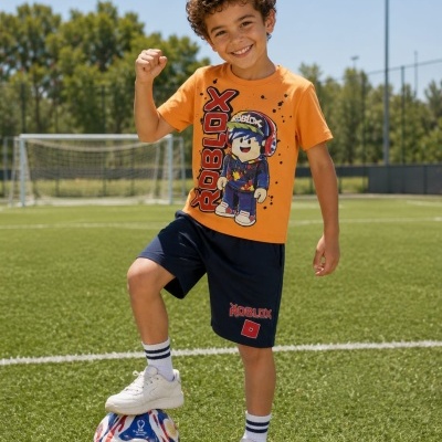 Menino com camisola laranja Roblox e calções azuis escuros em campo de futebol com bola colorida