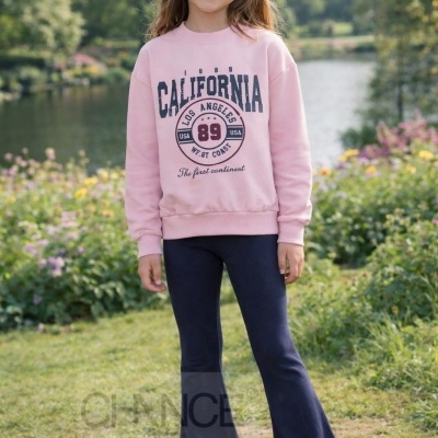 Menina com sweat rosa e calças azul-escuras num parque verde