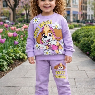 Menina sorridente com roupa lilás estampada PUPPY POWER! e ténis brancos