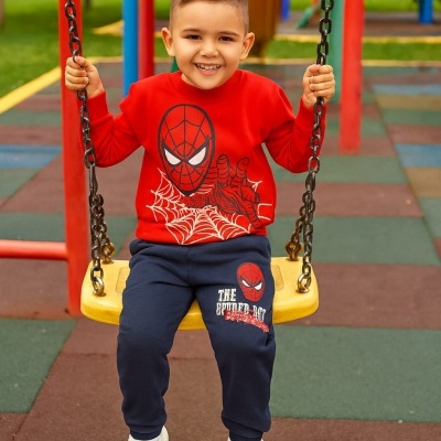 Criança com roupa do Homem-Aranha sentada em baloiço amarelo no parque infantil.